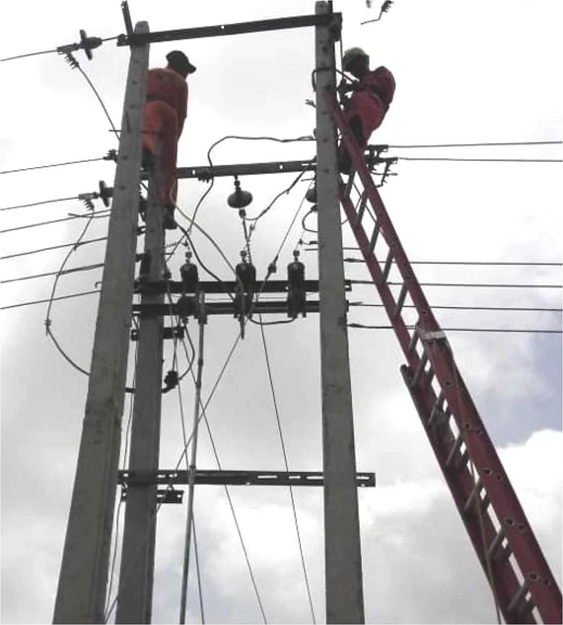 Linemen installing an 11kV cross-arm and conductors